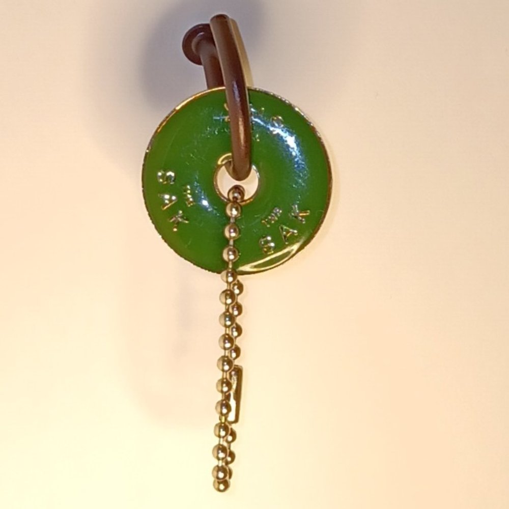 THE SAK EMBOSSED ROUND GREEN NICKEL METAL DISC KEY FOB BAG